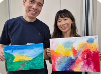 Two participants showing their colourful completed paintings